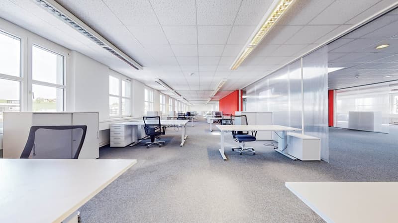 Office room with gray carpet, multiple desks, glass walls, white ceilings, bright windows, white office furniture