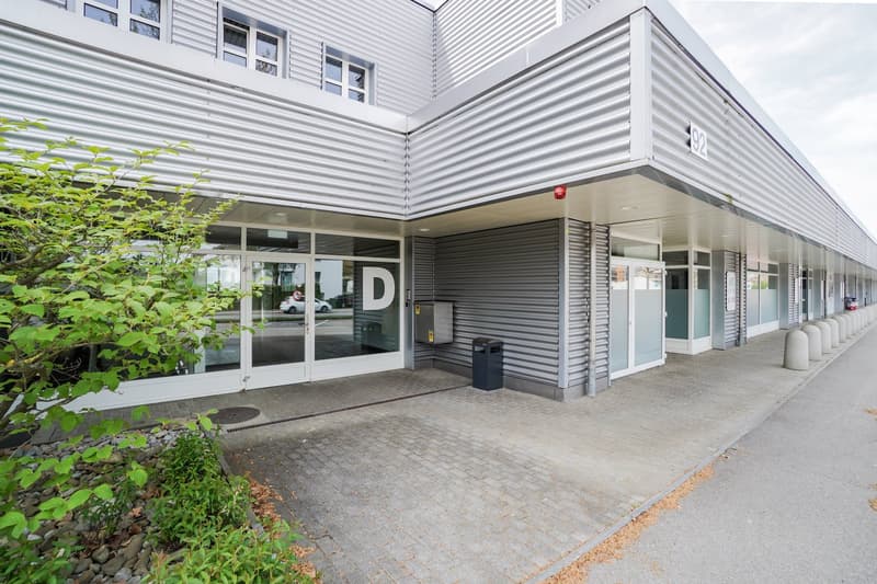commercial building, large entrance, glass doors, raised ground floor, several parking bollards