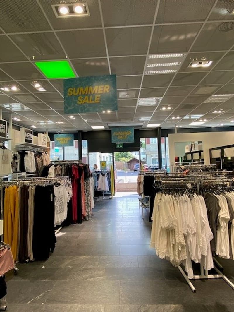 Rows of clothes on racks, promotional banners, clothing displays, hanging lamps, tiled floor