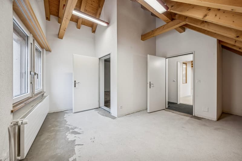 Large attic room, wood beams, white walls, glass windows, wooden flooring, doors