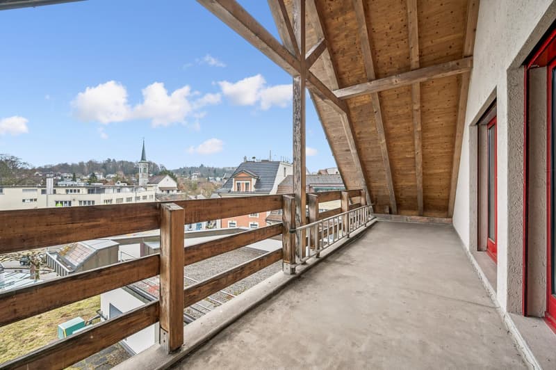 open wooden balcony with railings, view of town and landscape