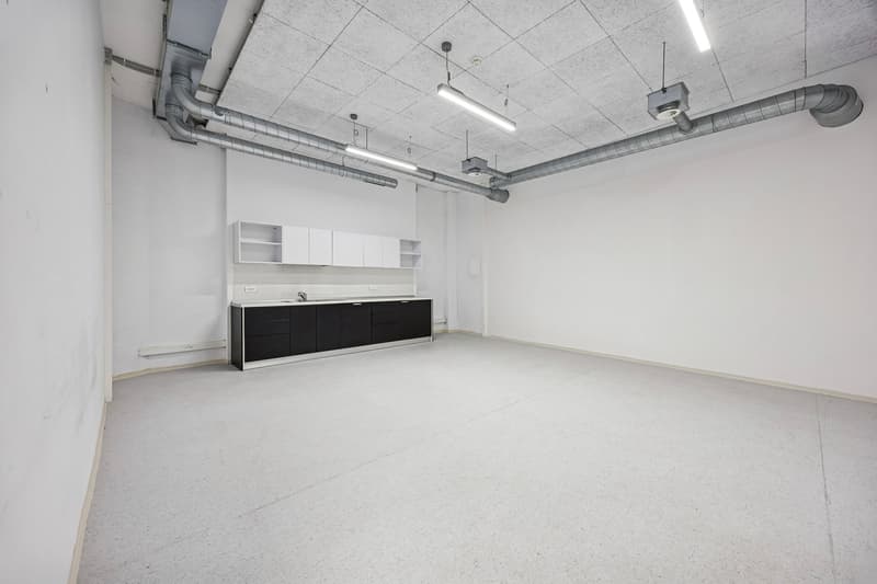 empty room with white walls, ceiling, and floor, cabinets and countertop, pipes