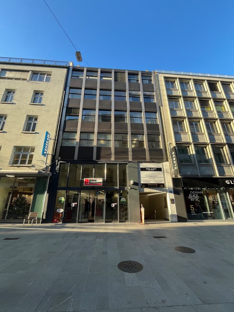 Modern office building, multiple windows, black and white exterior, Inter Discount store at entrance, large glass doors and windows, ground floor shop fronts