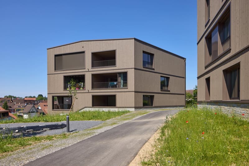 Raised ground floor, wooden exterior, balconies, sloping driveway