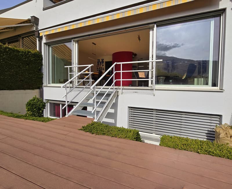 white building with wooden deck, steel railings, large windows