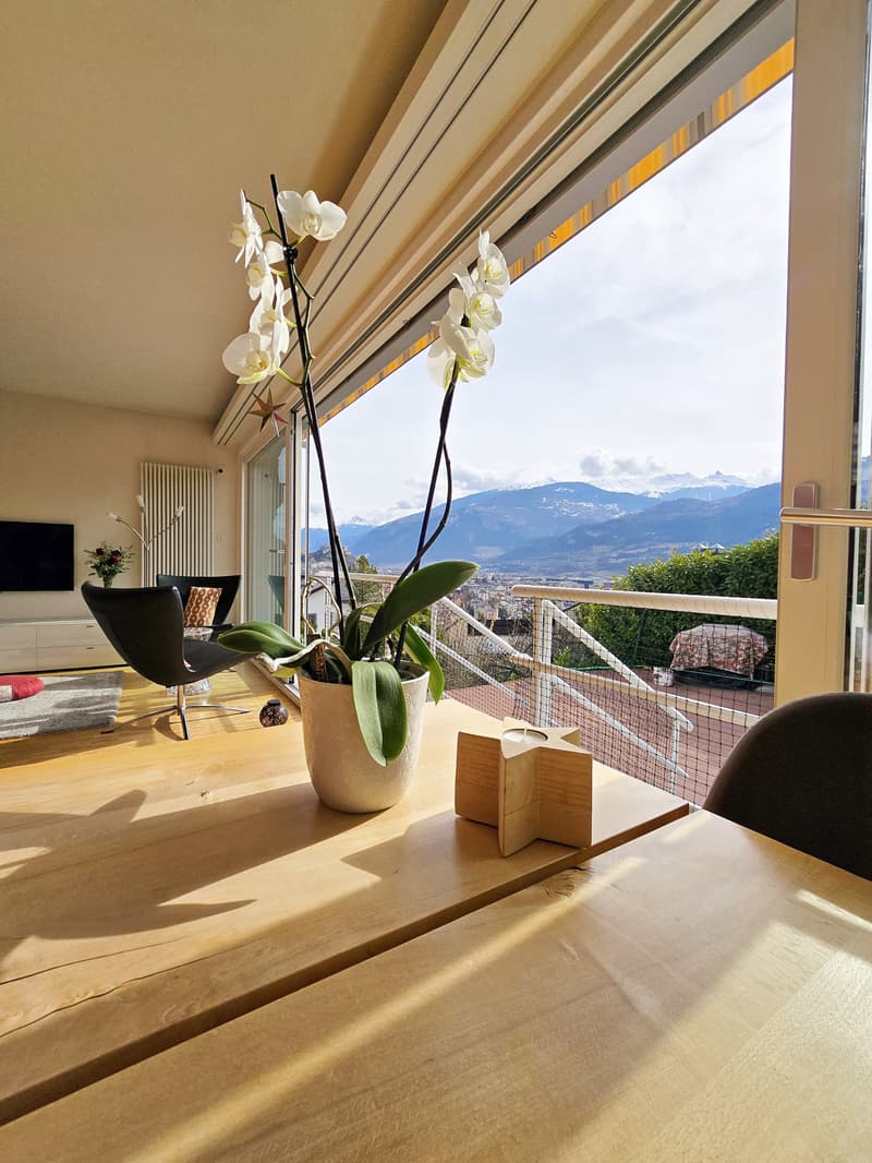 A table with a flower vase, a wooden chair, a side table, and a TV