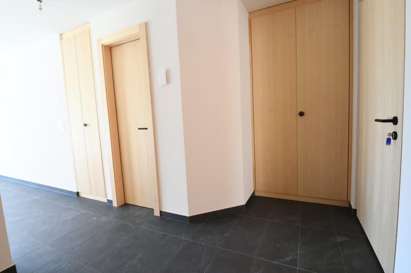 Empty hallway with tiled floors, two wooden doors, light on the ceiling.