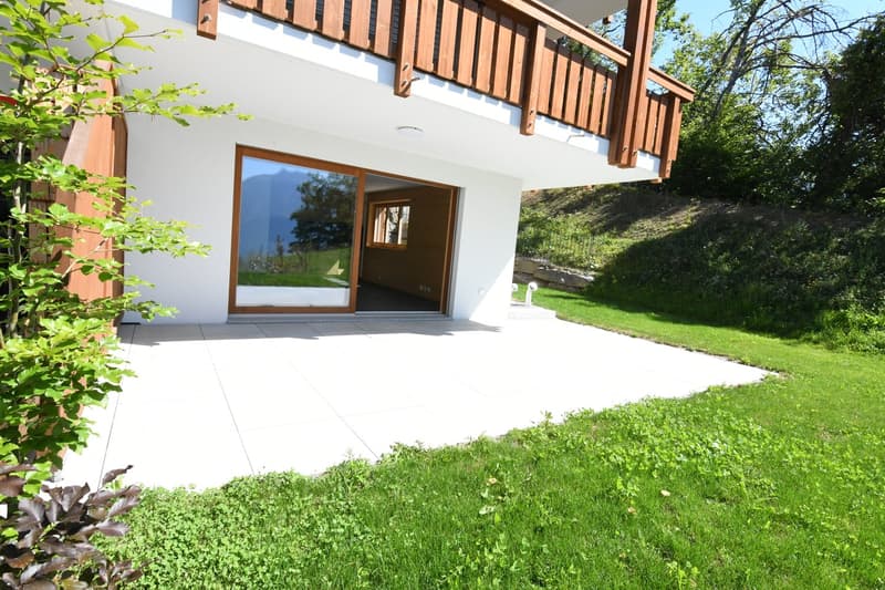 white exterior, wooden balcony, open sliding glass doors, tiled entrance, sloped lawn, white wall