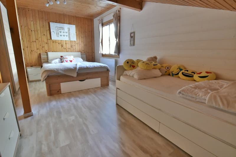 wooden walls, wooden floors, two single beds, nightstands, wardrobe, radiators, window with curtains, framed pictures on the wall, smiley face pillows