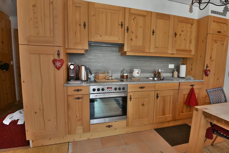 Rustic wooden kitchen cabinets, granite countertop, stainless steel oven and stovetop, small appliances, decorative heart-shaped ornaments