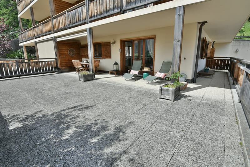 Balcony with seating area, stone flooring, potted plants, and views of the surrounding area.