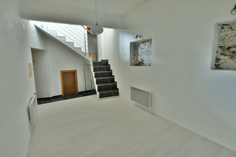 open-plan layout with a staircase leading upstairs, white floors, white walls