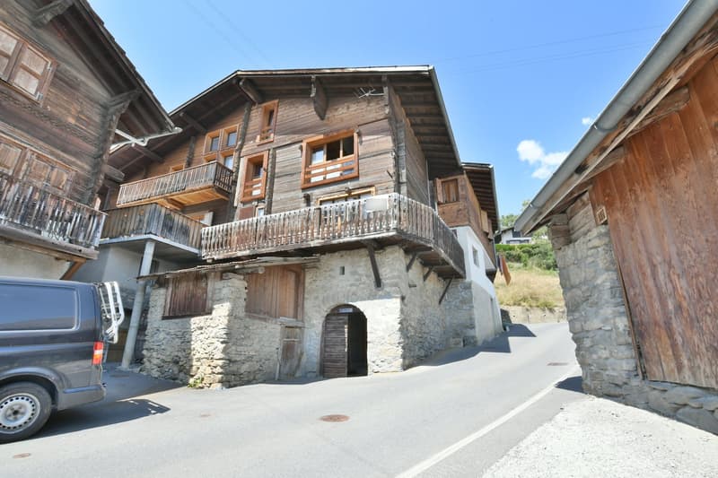Stone and wooden building, balconies, doors, windows, archway entrance, concrete road