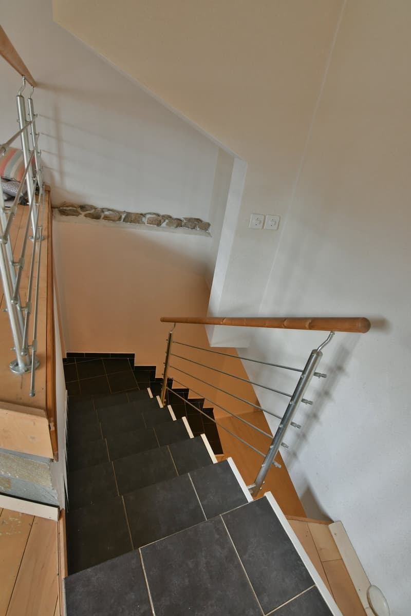 Wooden steps, metal handrail, wooden handrail, tiled flooring, light-colored walls
