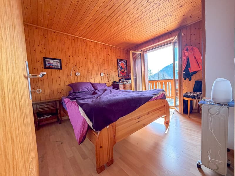 wooden bed, purple blanket, wooden nightstand, wooden wall, wooden floor, open balcony