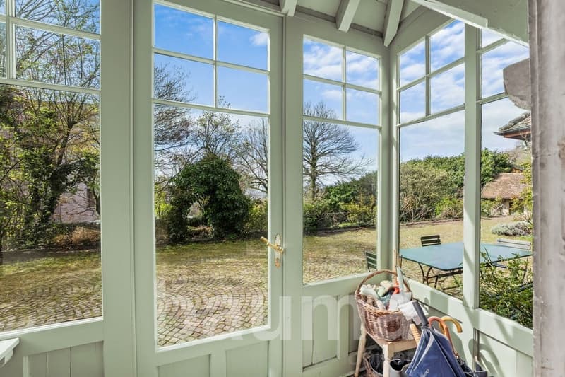 glassed windows and doors, view of a green field, wooden basket, table, chairs, umbrellas