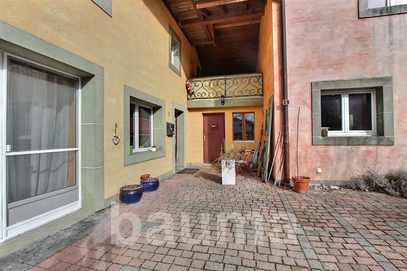 yellow building with terracotta pots, brick paved courtyard, balcony