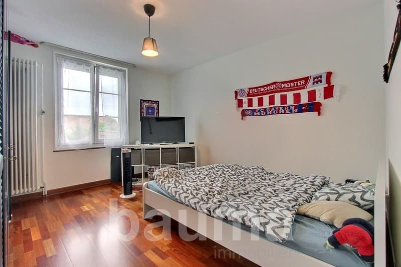 bedroom with bed, television, storage boxes, radiator, window, lamp