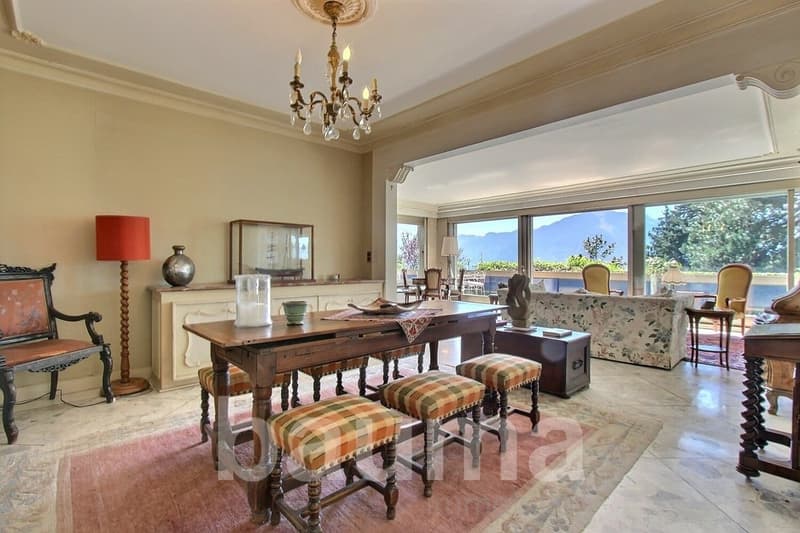 dining room with large windows, wooden table, chairs, chandelier, carpet, side table, lamp, cabinet, couch, side table, sculpture