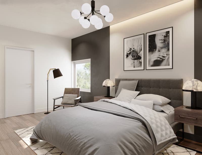 bed with gray duvet, wooden nightstands with lamps, rug, chair, wall with two photos, lamp, window