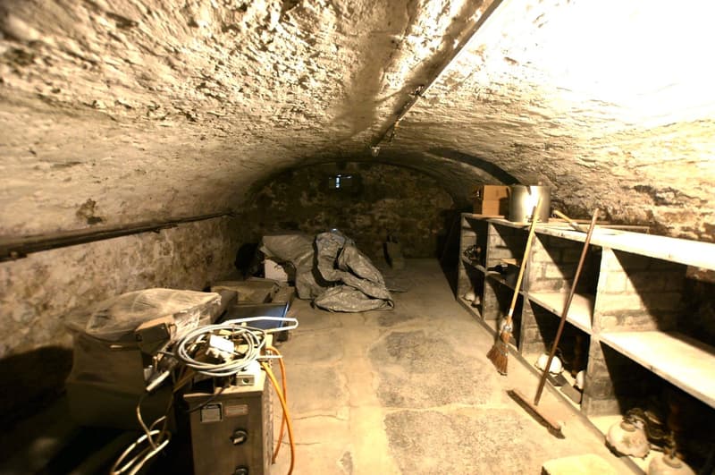 stone walls, stone floor, storage boxes, buckets, brooms, wires, electrical box