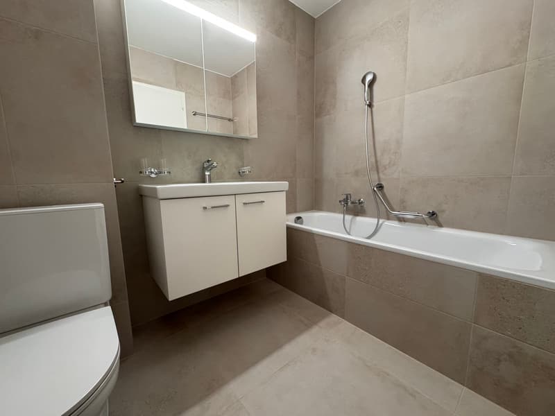 modern bathroom with beige tiles, white sink, white bathtub, and white toilet