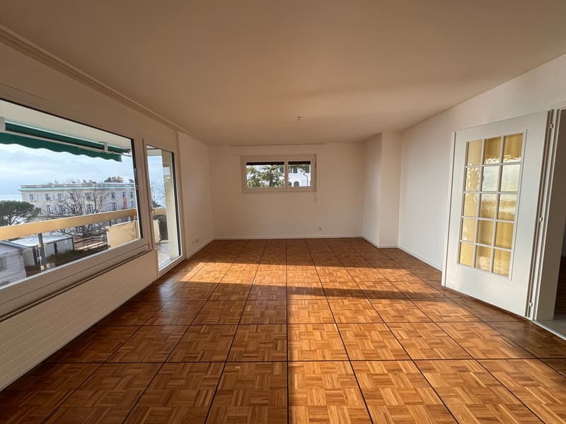 large room, wooden tiles, windows with balcony access, large windows