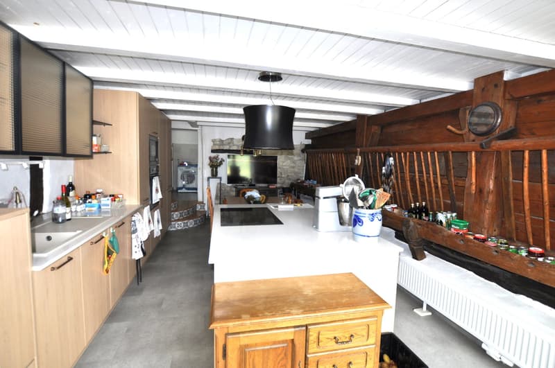 Rustic kitchen with wooden beams, cabinets, and countertops. Includes a dishwasher, stove, and various kitchen appliances and utensils.