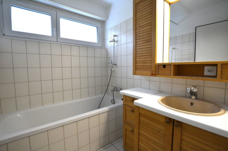 modern bathroom, white tiled walls, bathtub, sink, mirror, wooden cabinets, shower head