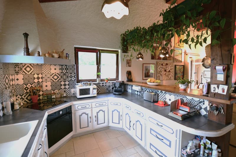 white kitchen with tiled wall, white cabinets, black tiled counter, microwave, toaster, bowl, sink, black stove