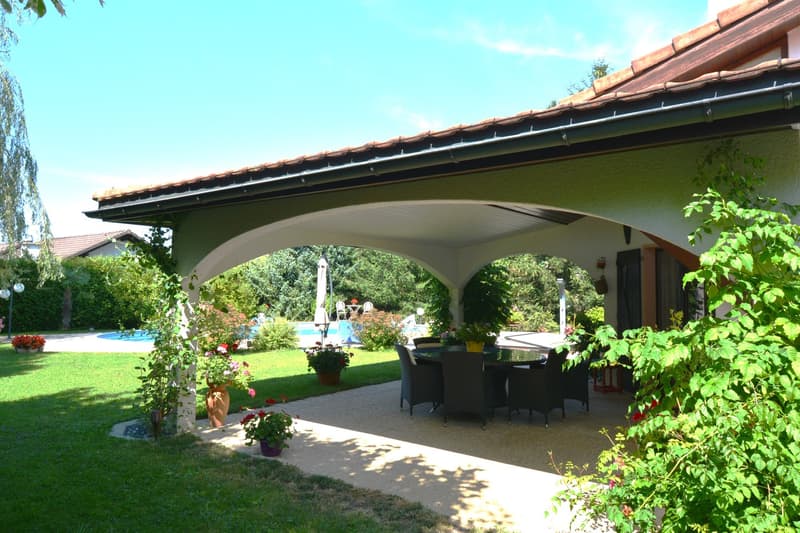 Outdoor seating area with table and chairs, green space, swimming pool, house