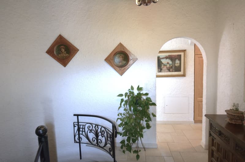 tiled floor, picture frames on wall, decorative plant, metal bench, wooden cabinet