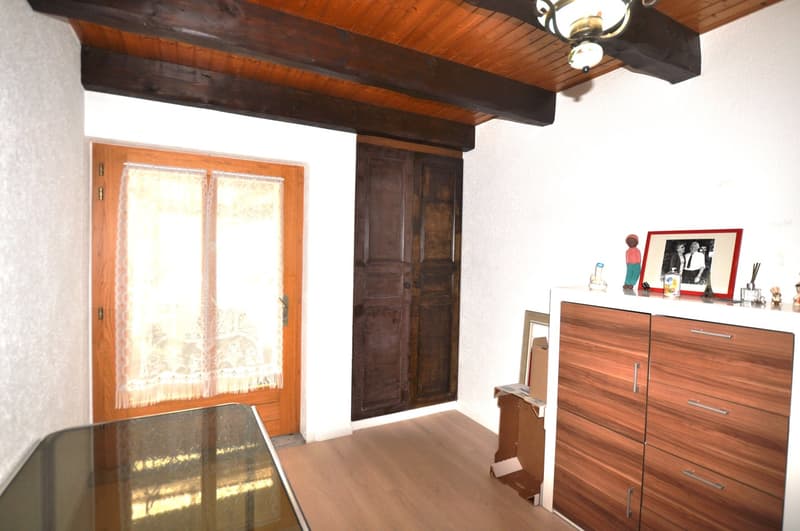 a room with wooden beam, wooden door, wooden window, glass table, wooden cabinet, picture frames