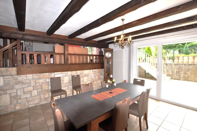 dining room, chandelier, brown chairs, long table, stone wall, radiator, clock