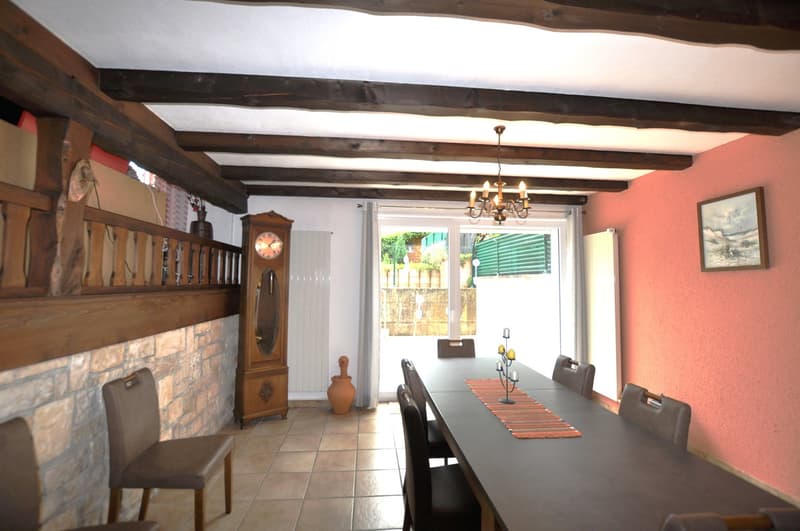 Long wooden table, chairs, chandelier, wooden cabinet, brick wall, fireplace