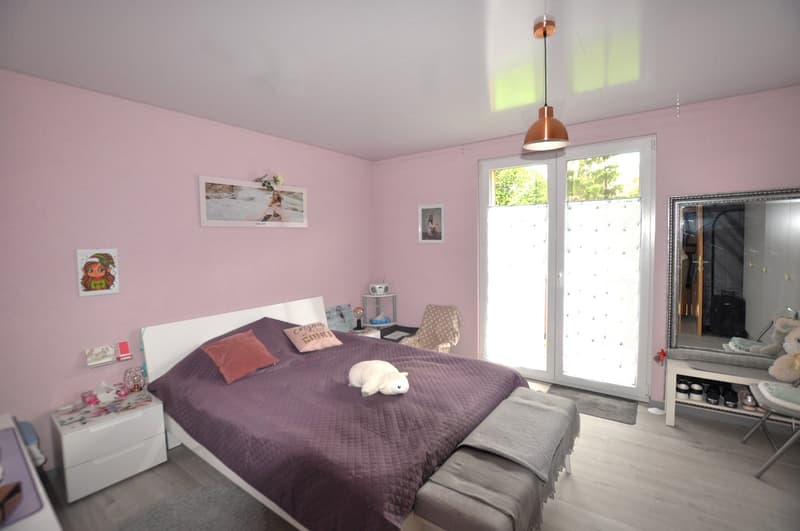 modern design, pink walls, large bed, bedside tables, chair, mirror, glass door leading to a balcony, decorative items, framed pictures