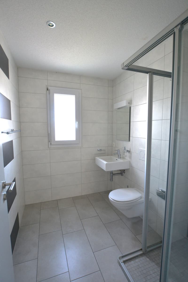 tiled floor, white walls, white sink, glass shower enclosure, white toilet, mirror, window