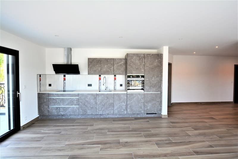 modern kitchen with granite countertops, gray cabinets, stainless steel appliances, wooden floor, sliding glass door to balcony
