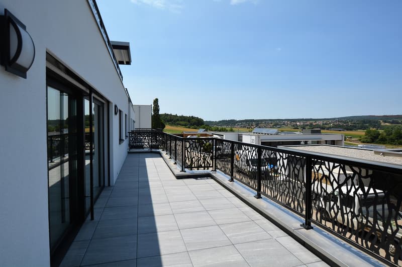 building with a balcony, tiled floor, black railing, panoramic views of the surrounding countryside