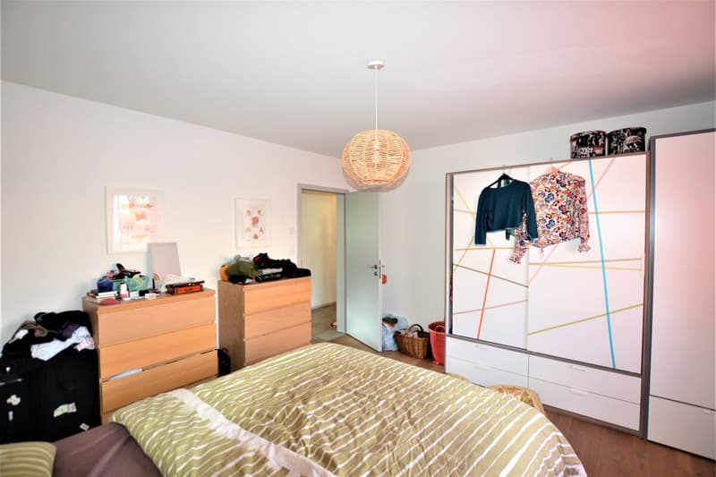 bedroom with bed, two wooden dressers, and a wardrobe with colorful wall art
