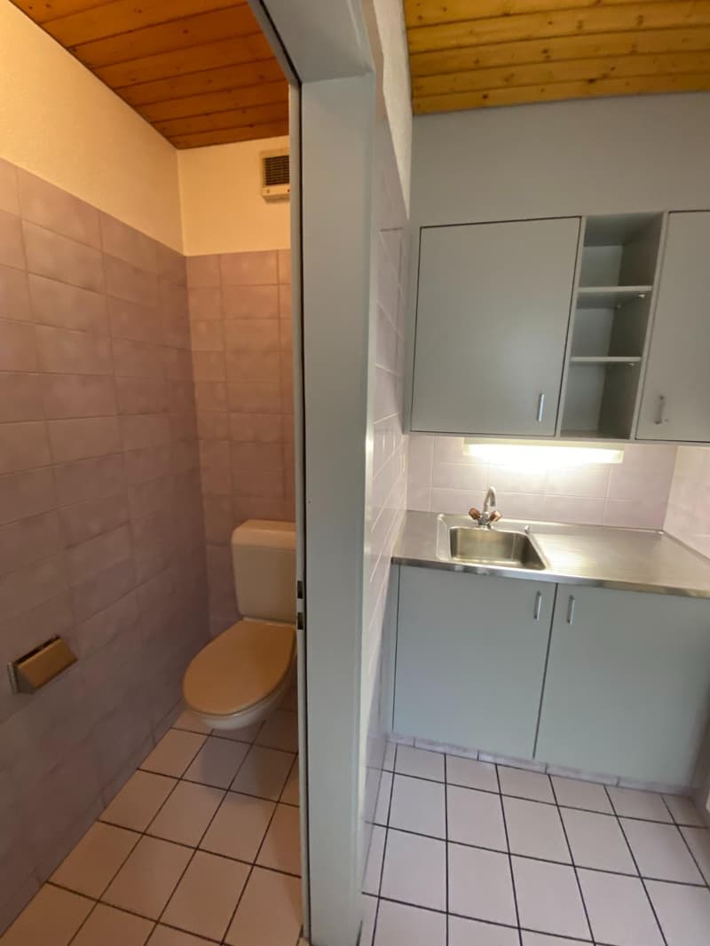 Small bathroom with toilet, sink, cabinets, and tiled floor