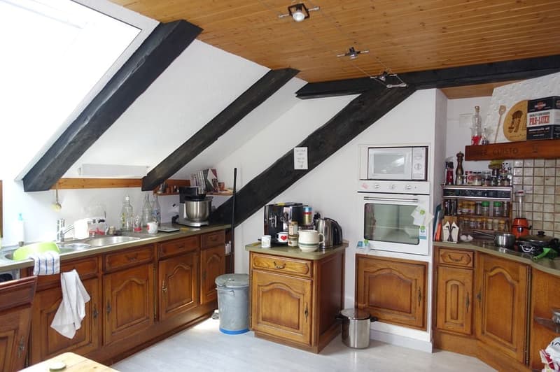 kitchen with wooden cabinets, sink, faucet, microwave, oven, kitchen tools, trash bin, wooden beams, skylight