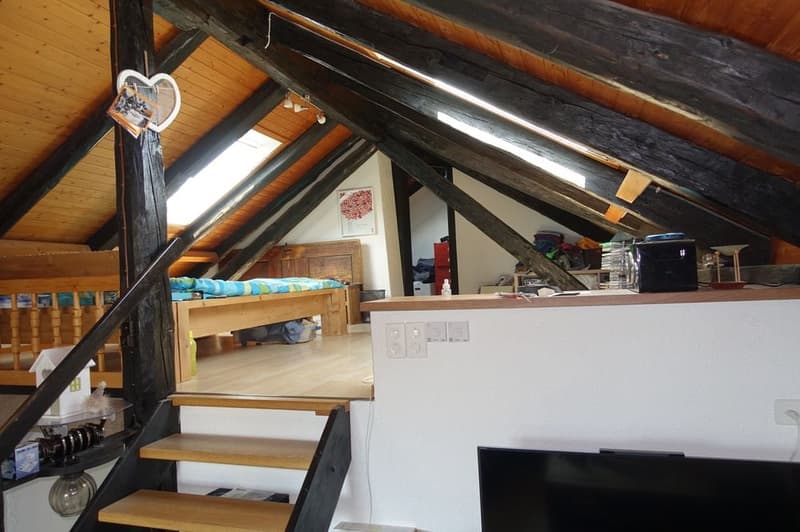 Exposed wooden beams, wooden floor, small wooden bed, sofa bed, wooden table, black television