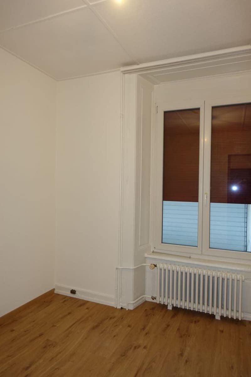 empty room, white walls, wooden floor, radiator, windows