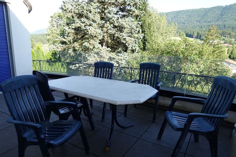 6 plastic chairs around a white table, with a beautiful view of the valley