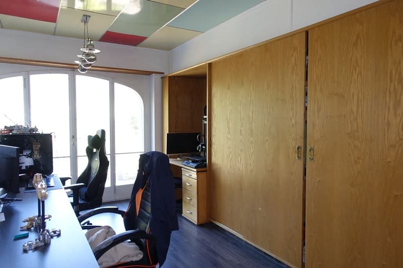 Home office with desk, gaming chair, computer, cabinet, and window