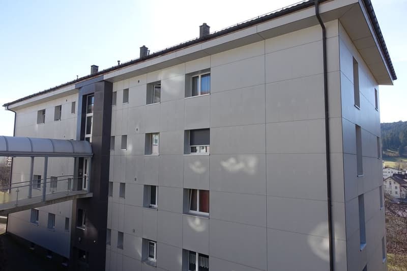Apartment building with multiple floors and a covered entrance walkway.