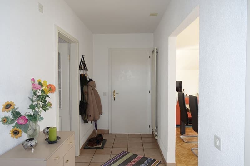 Decorated hallway, flowers, tiled floor, shoes, jackets, rug