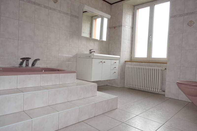 Bathroom with bathtub, sink, mirror, radiator, and toilet.