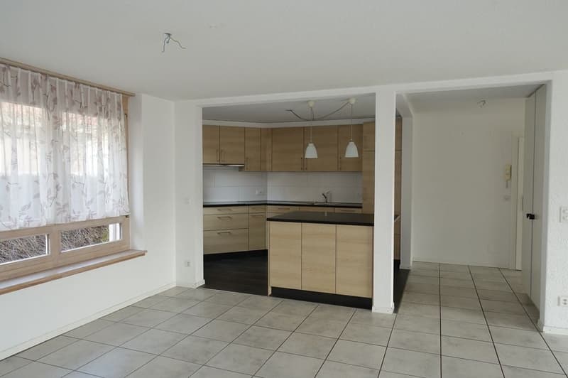 empty kitchen with wooden cabinets, black countertop, white tiled floor, window with curtains, sink with faucet